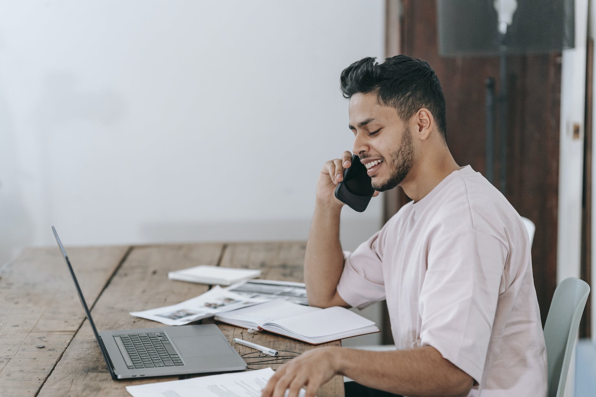 Happy businessman speaking on phone at workplace